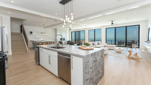 Una cucina moderna con isola centrale, zona pranzo e angolo salotto con vista sull'oceano.