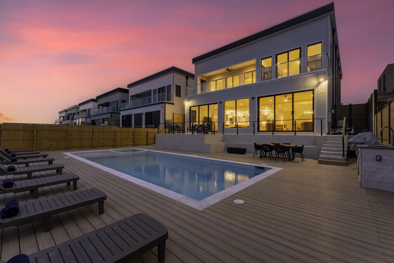 En modern byggnad med en swimmingpool, utomhusmöbler och ett trädäck.