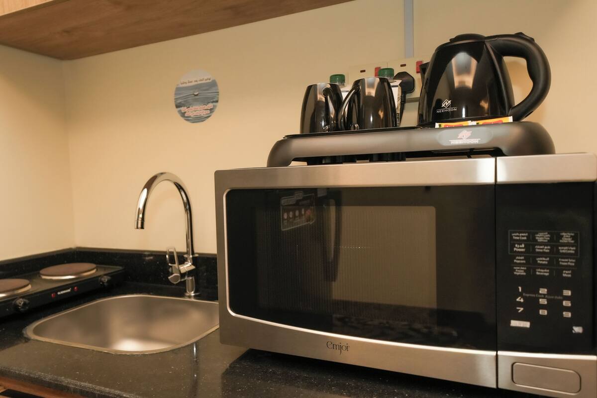 A kitchen with a microwave, a sink, and a kettle.