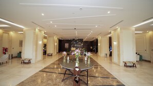 A spacious hotel lobby with a central round table, seating arrangements, and a reception desk. - benzrthotel (Al-Hofuf)
