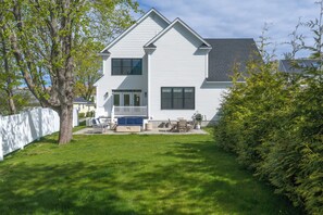A two-story house with a front porch, a lawn, and a tree. - Downtown Coastal Charm Cottage in Kennebunk (Kennebunk)