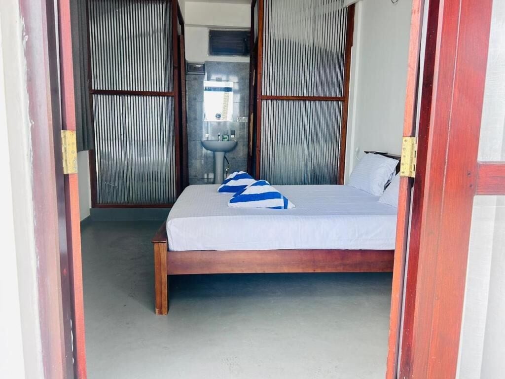 A bedroom with a wooden bed, a white mattress, and a blue and white striped blanket.