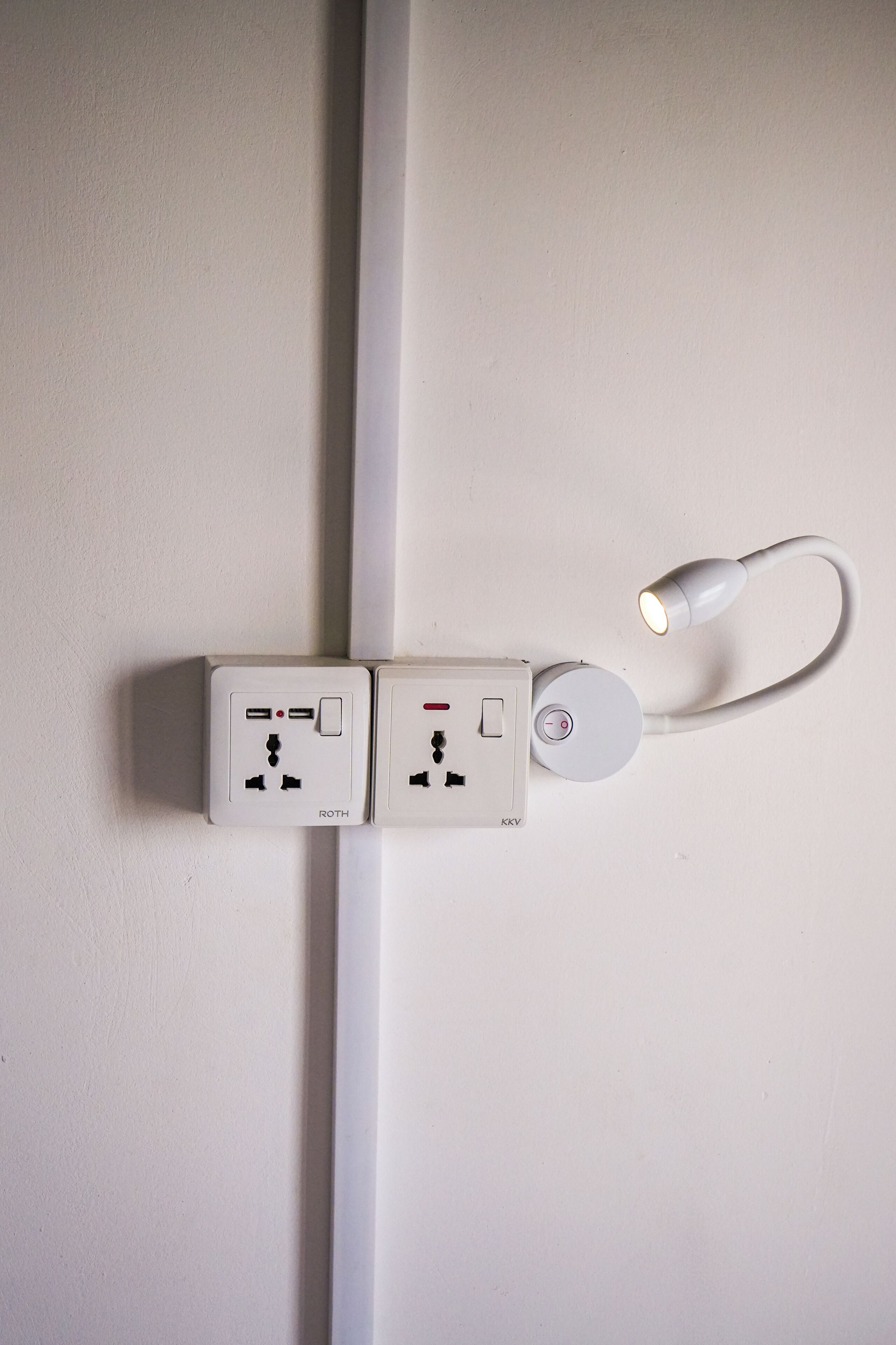 Twee stopcontacten en een USB-laadpoort op een witte muur.