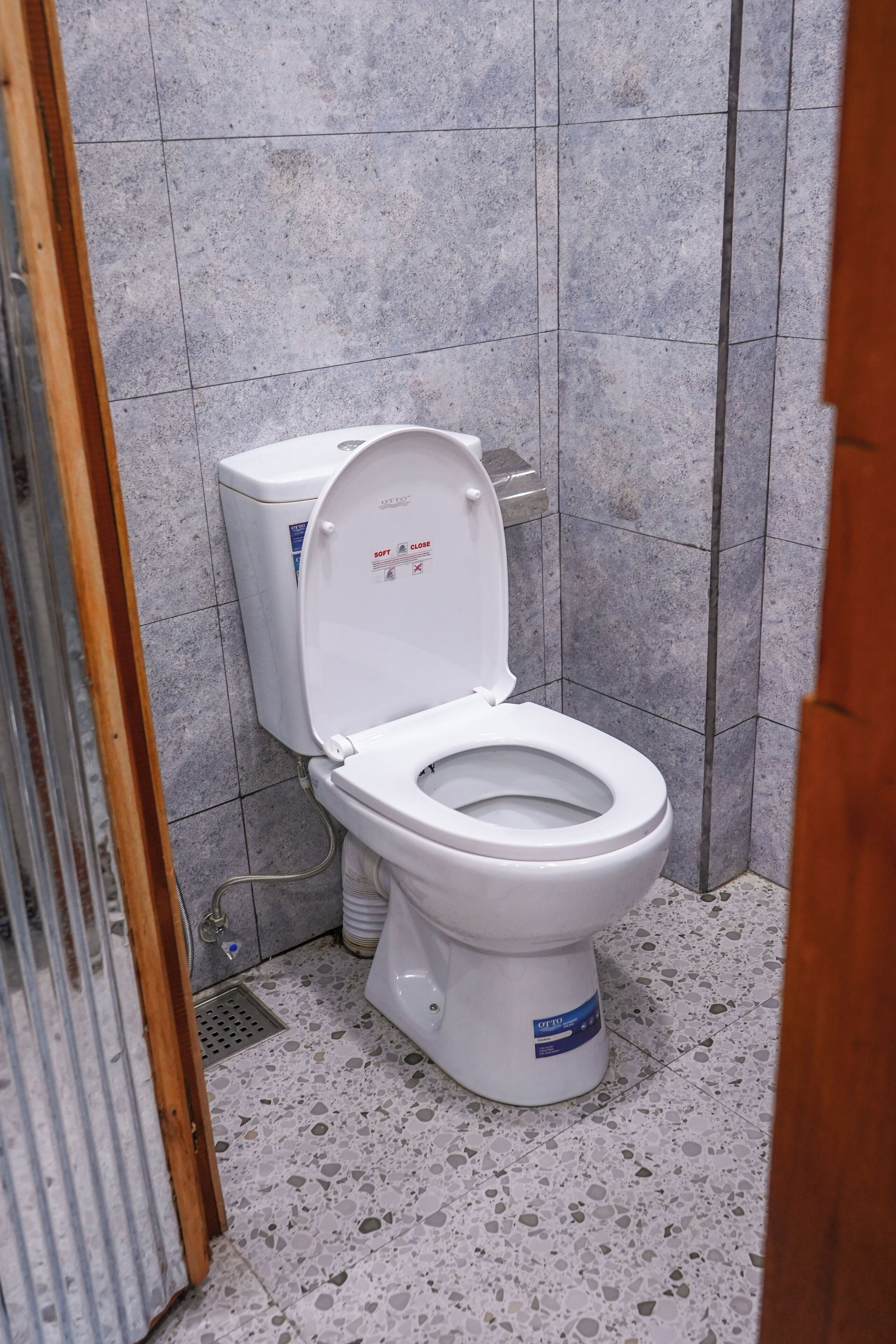A bathroom with a white toilet, a shower area, and a tiled floor.