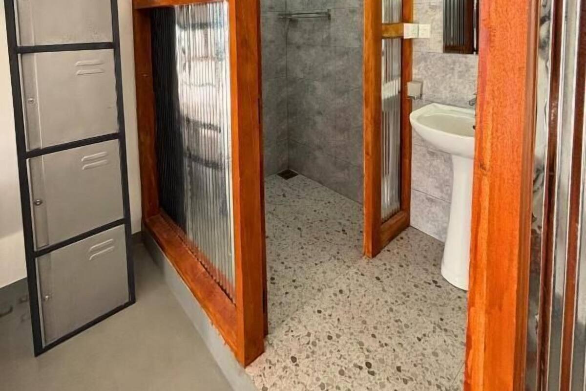 A bathroom with a shower, a sink, and a metal cabinet.