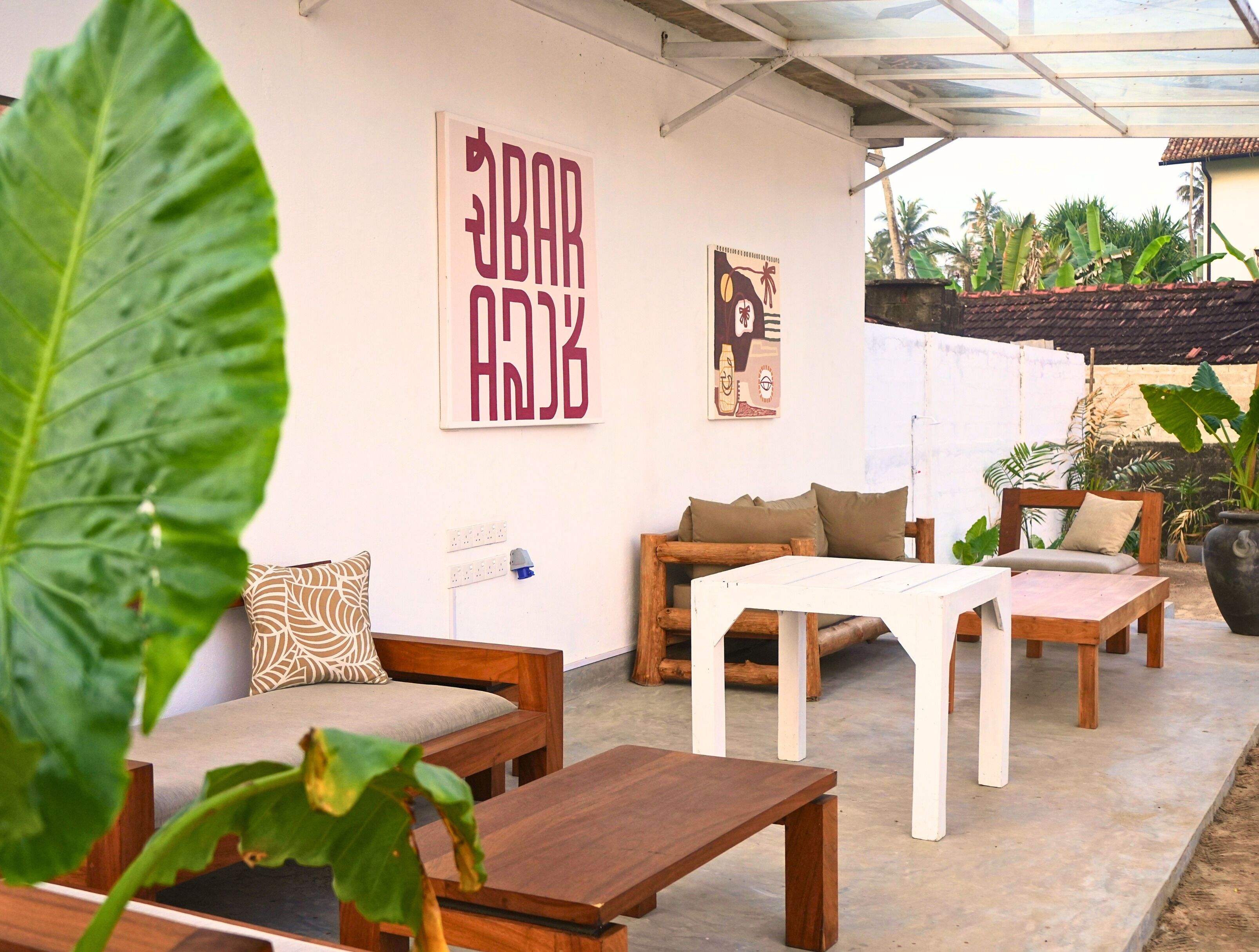 A covered outdoor seating area with wooden furniture and a white table.