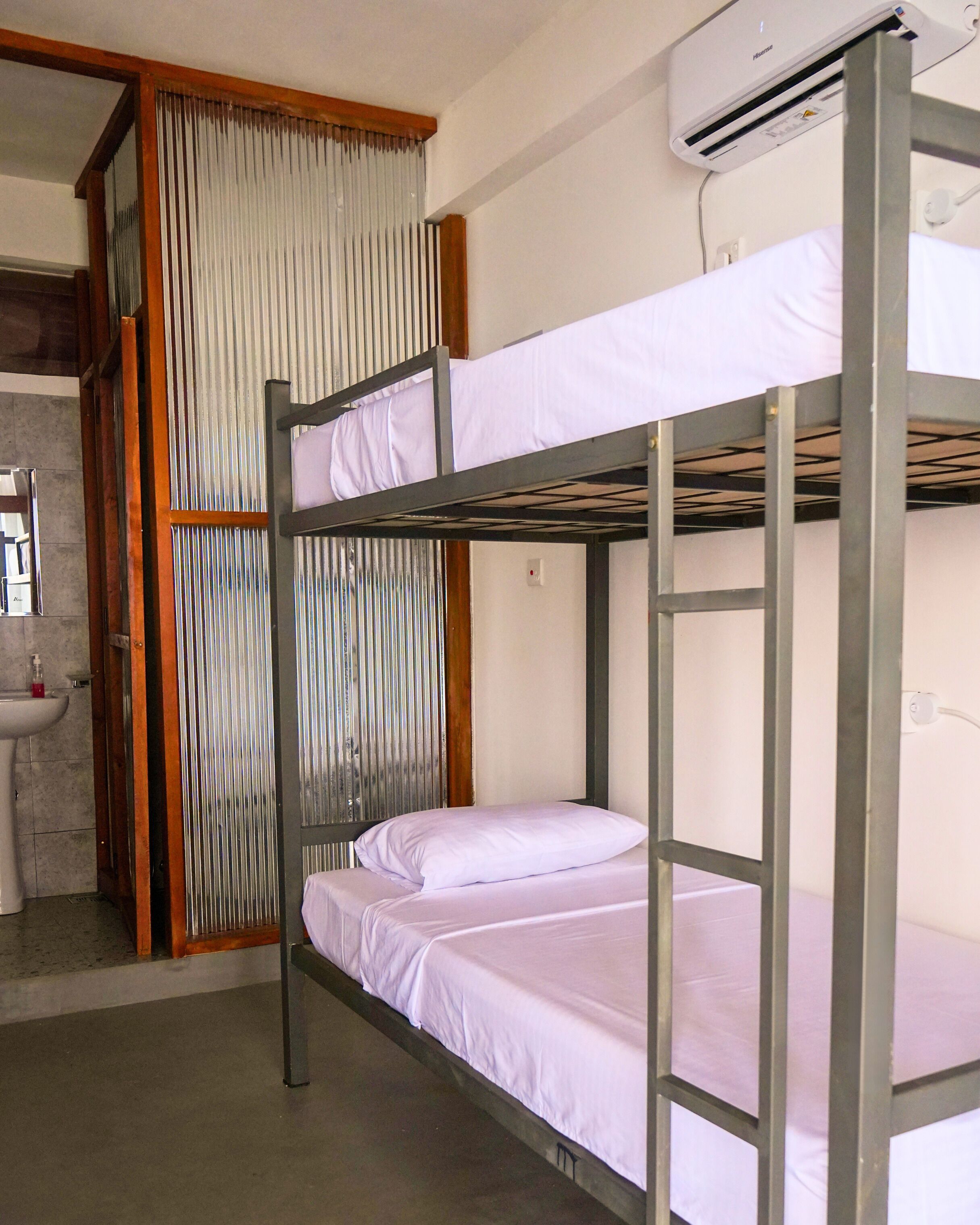 Habitación con literas, ventana, lavamanos y aire acondicionado.