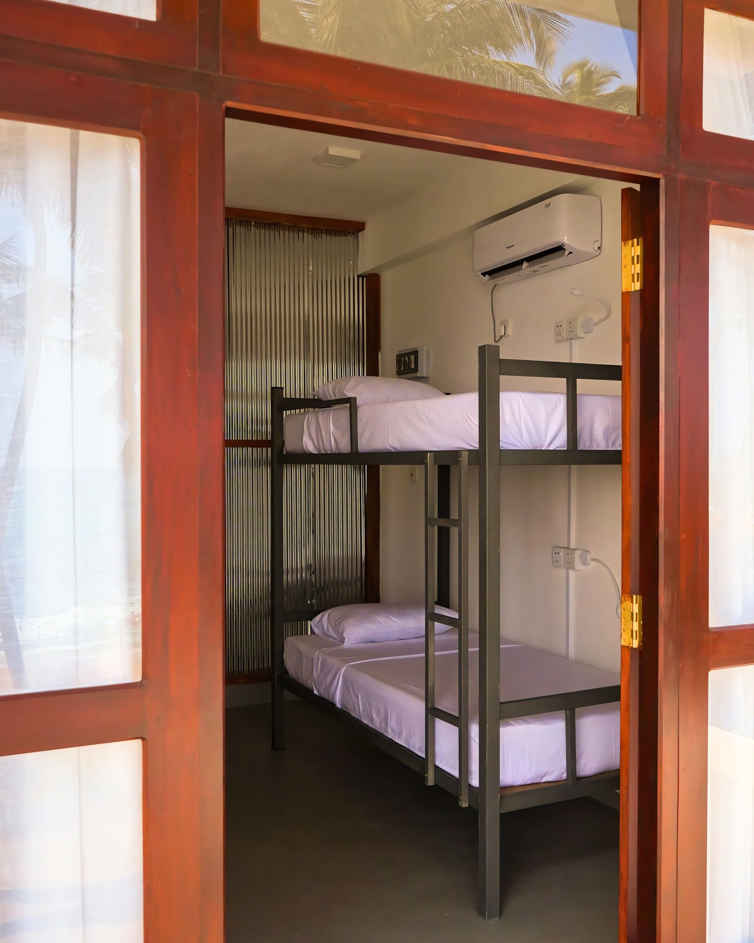 A bunk bed room with a window, curtains, and a power outlet on the wall.