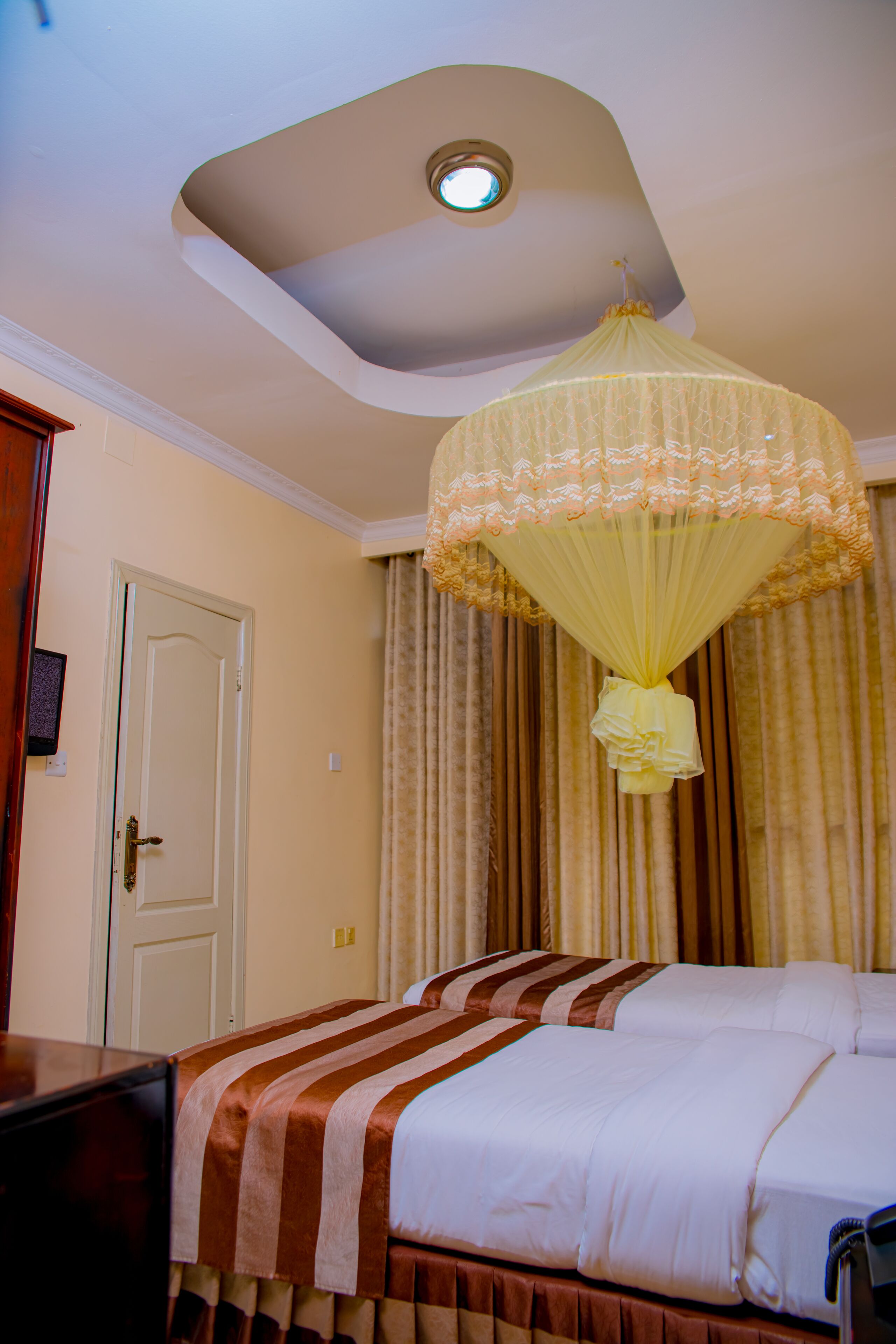 Habitació d'hotel amb un llit, un escriptori, una làmpada al sostre i cortines.