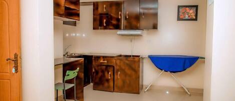 Una cocina compacta con armarios de madera, un pequeño comedor y un tendedero azul.