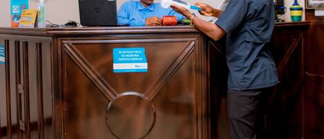 A reception desk with a digital screen, a laptop, and a sign indicating a service area.