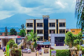 A hotel named 'SNOW HOTEL' with a prominent sign, surrounded by greenery and a view of a mountain in the background. - INEZA HOTEL (Ruhengeri)