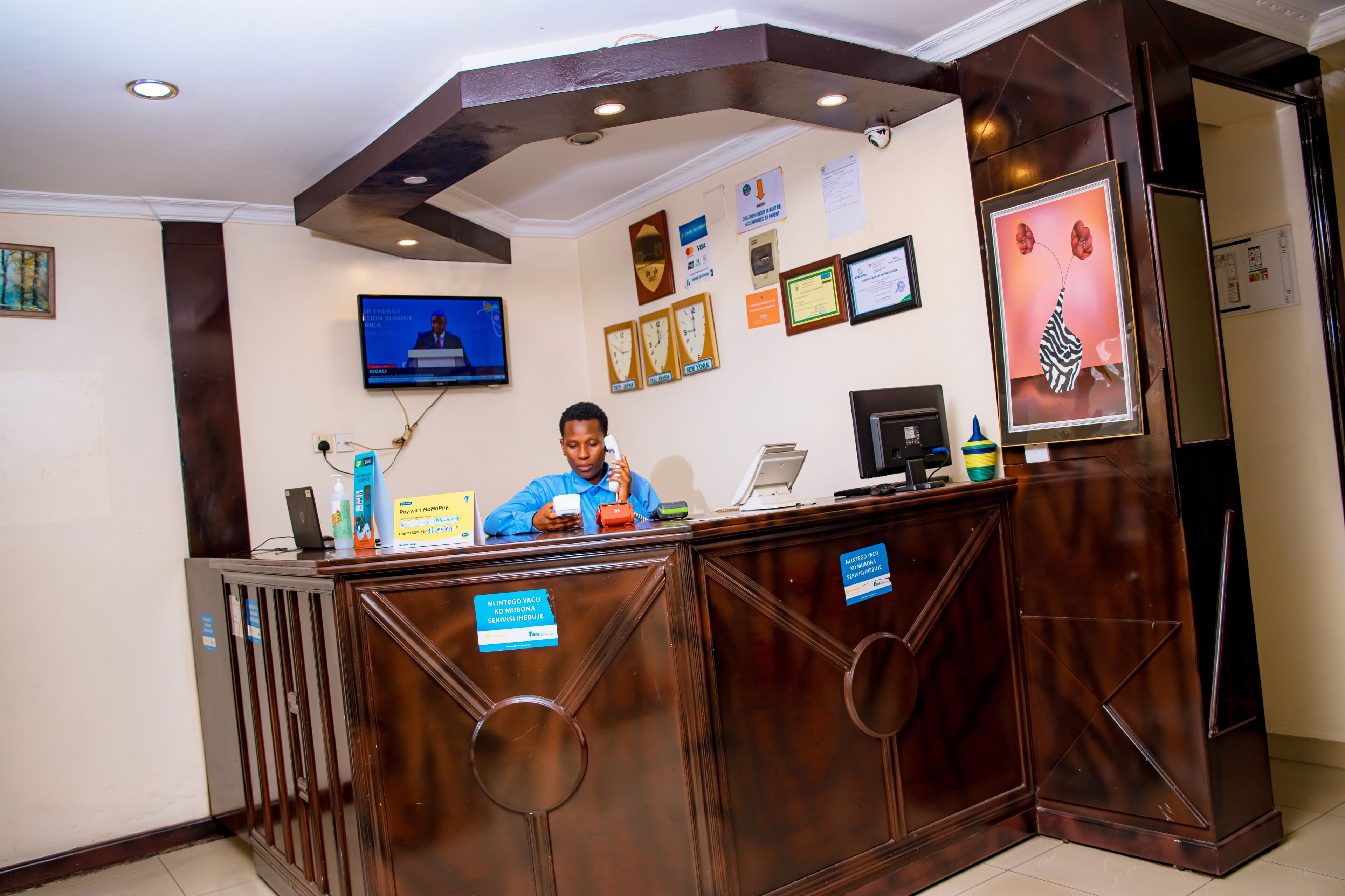 A reception desk with a TV screen, framed certificates, and a vase with flowers.