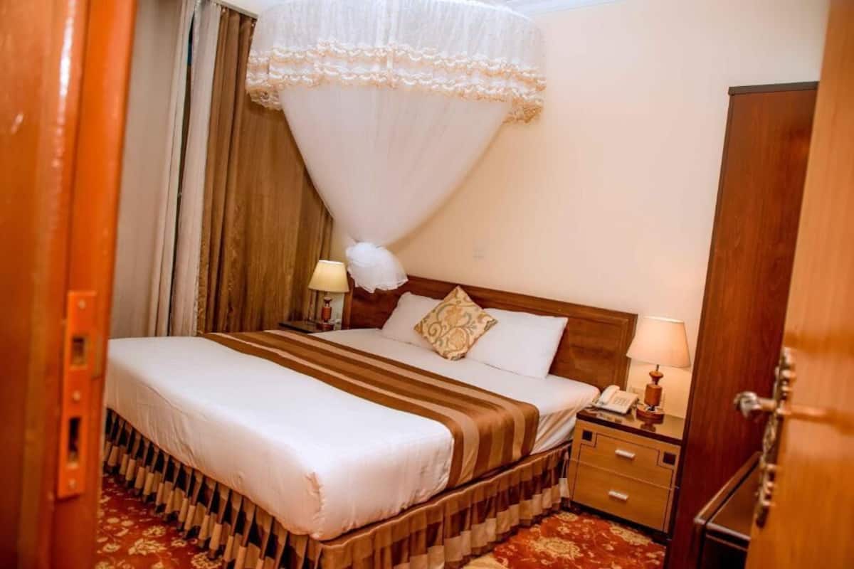 A hotel room with a bed, bedside tables, a wardrobe, and a canopy bed.