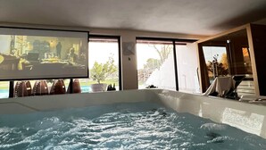 A hot tub in a room with large windows, a view of the outdoors, and a television screen. - Torre Menerva Viterbo Stunning Tuscia Villa,Private Spa + Sauna + Saltwater Pool (Lazio)