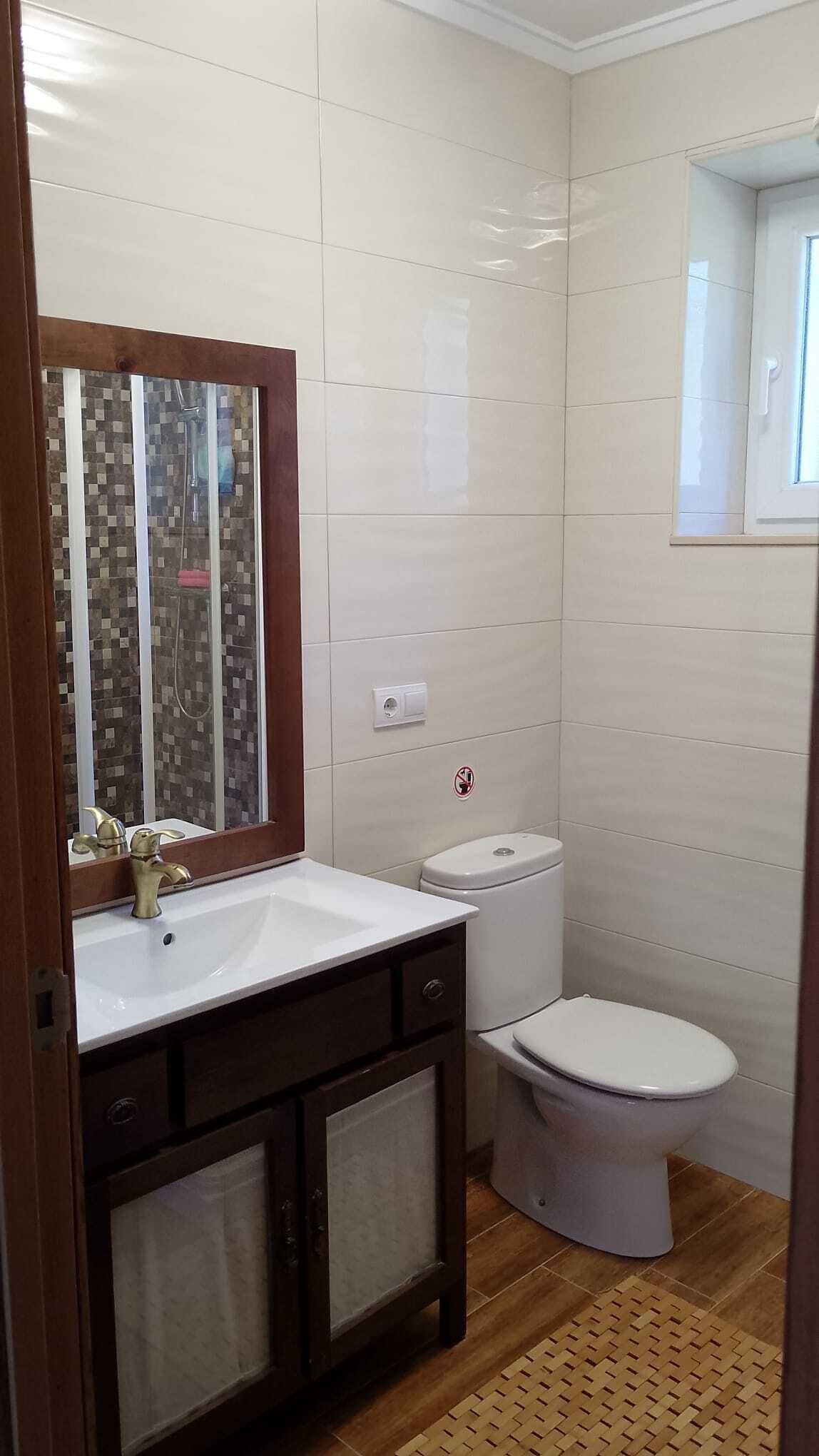 Un bagno con lavandino bianco, uno specchio, un WC e una zona doccia.