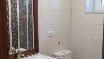 Un bagno con lavandino bianco, uno specchio, un WC e una zona doccia.