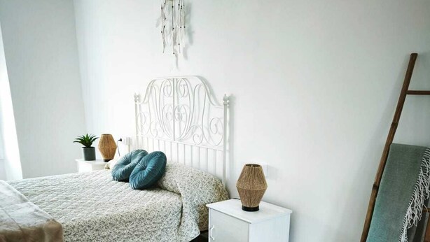 A bedroom with a bed, bedside table, and a decorative dreamcatcher on the wall.