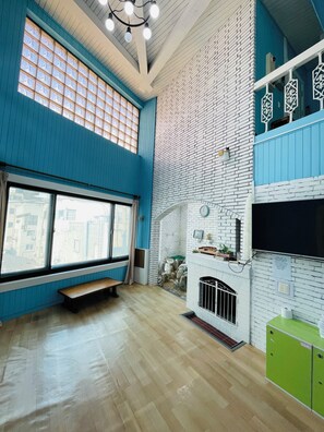 A spacious room with a large window, a fireplace, and a green cabinet.