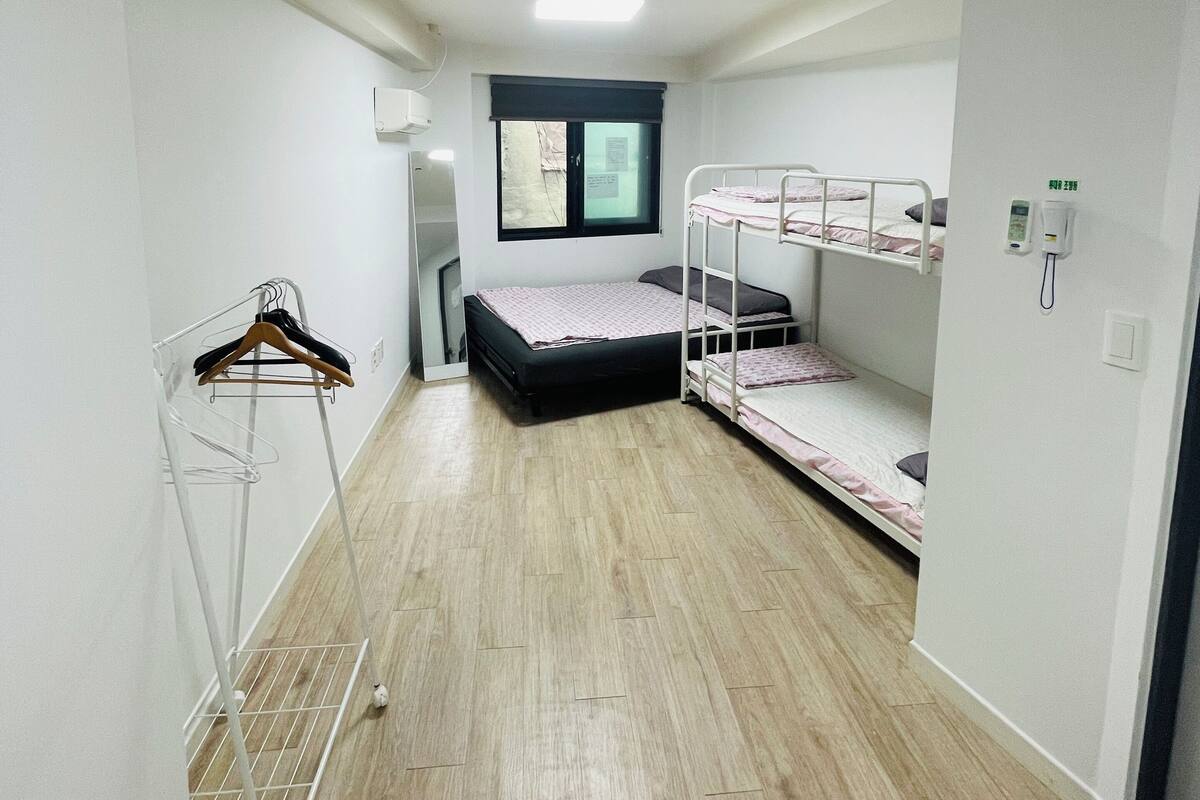 A room with bunk beds, a drying rack, a window, and a door.