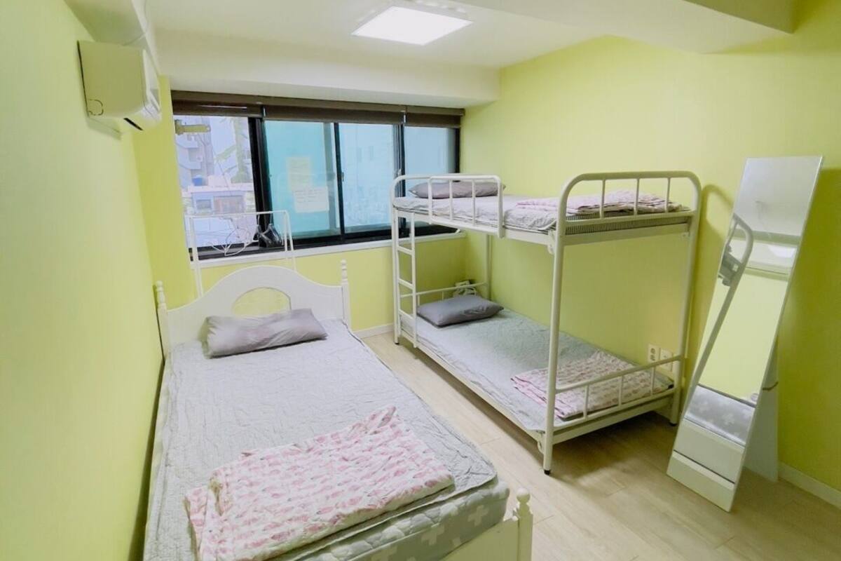 A room with a bunk bed, a single bed, and a desk.
