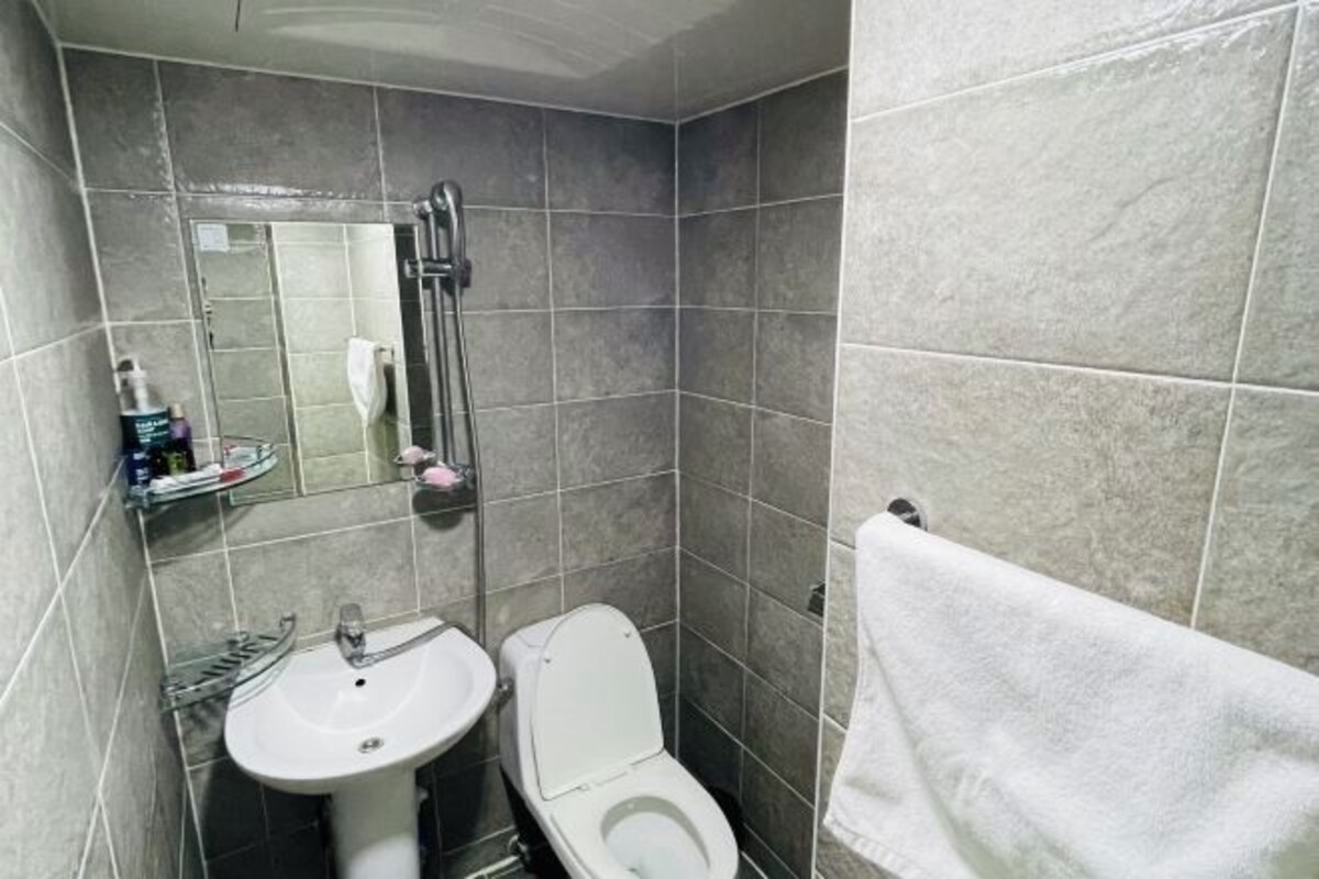 A bathroom with a sink, toilet, mirror, and towel rack.