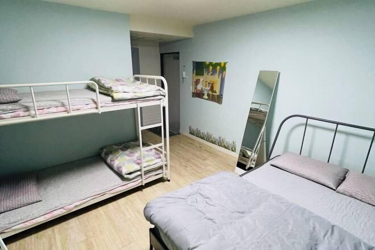 A room with bunk beds, a bed, a mirror, and a painting on the wall.