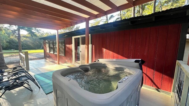 A hot tub under a wooden pergola with a red wall in the background. - GUEST HOUSE "GROOVY" PRIVATE HOT TUB ON DECK, WIFI, ROKU. (Kennard)