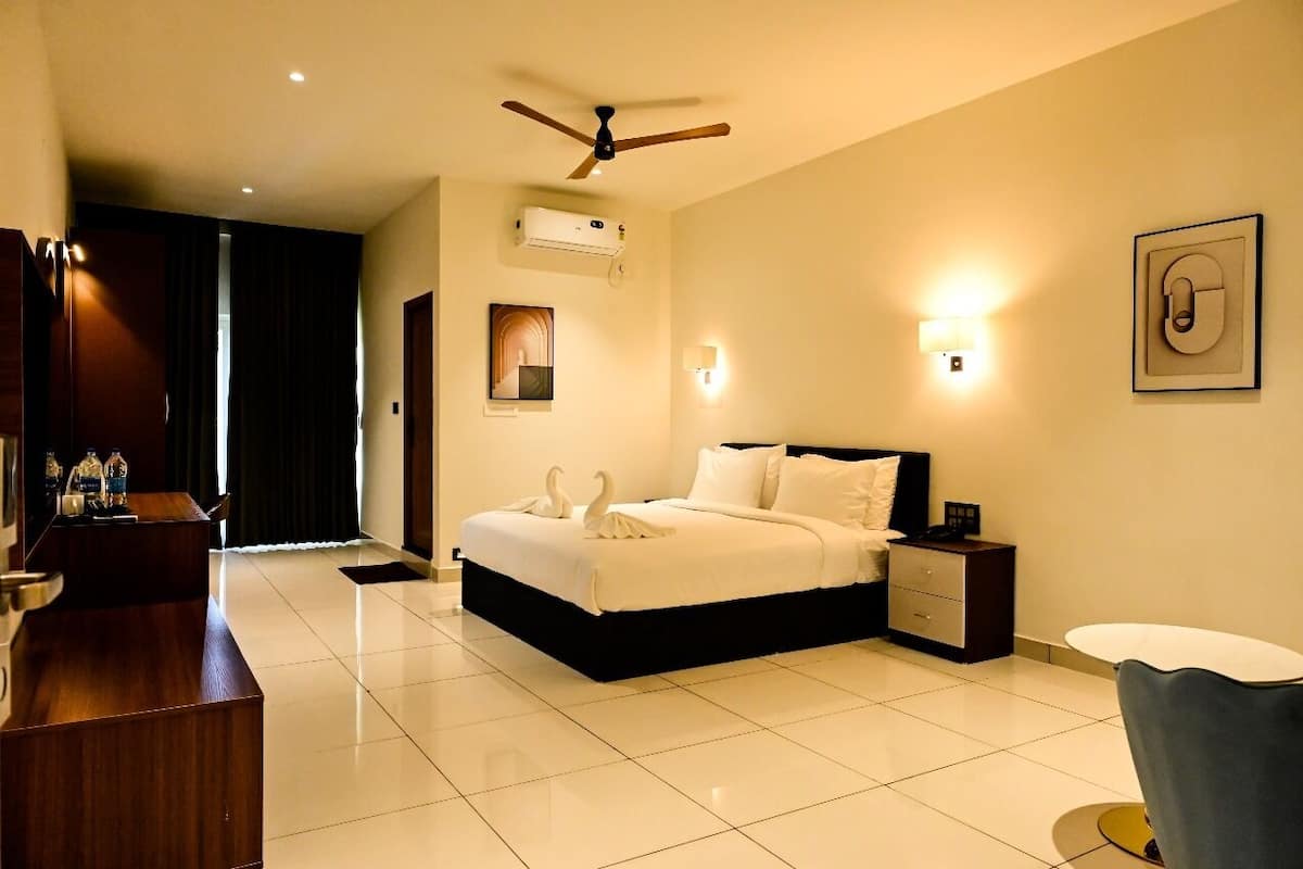 A hotel room with a bed, bedside table, nightstand, and a desk with a chair.