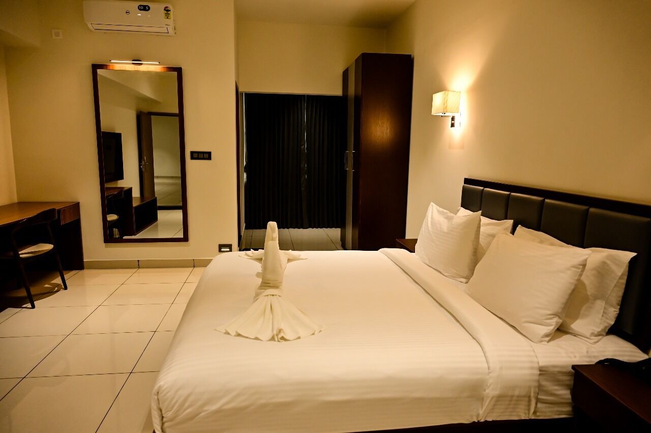 Una habitación de hotel con cama, escritorio, silla, espejo y armario.