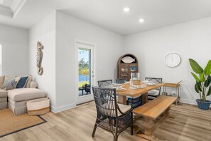 Un comedor con una mesa de madera, sillas y un reloj en la pared.