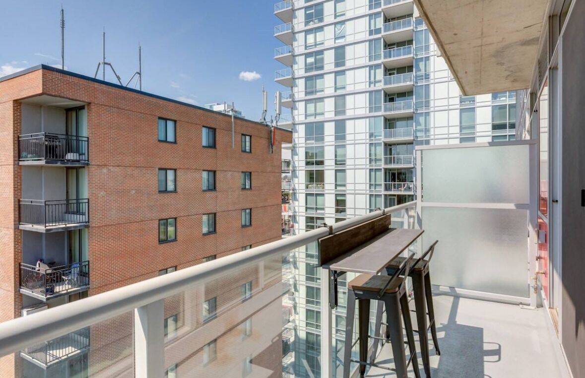 Een modern appartementencomplex met een balkon, voorzien van een houten tafel en stoelen.