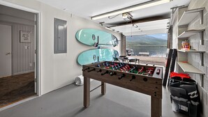 Een kamer met een tafelvoetbaltafel, twee surfplanken en uitzicht op het strand.