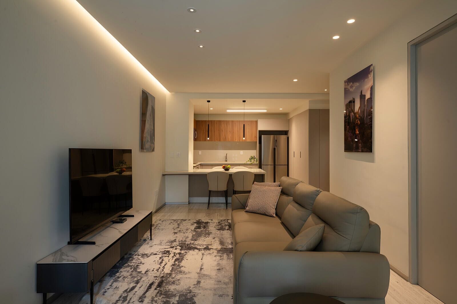 A modern living room with a sofa, a TV, and a dining area with chairs and a table.
