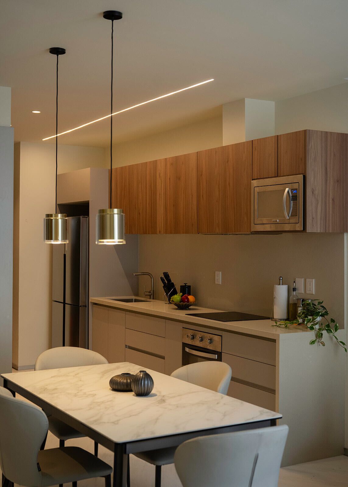 Una cocina moderna con armarios de madera, microondas integrado y encimera de mármol.