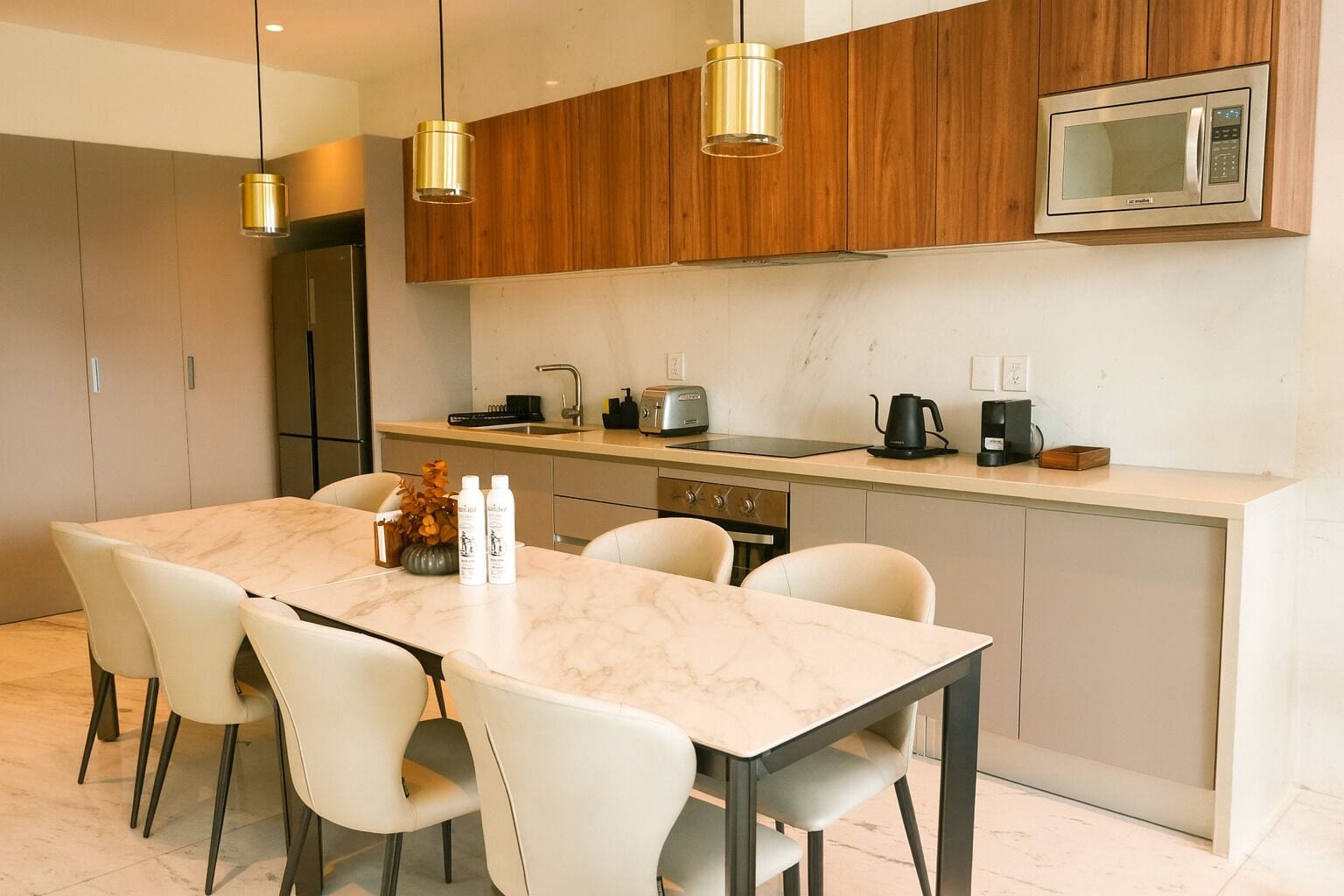 Une cuisine moderne dotée d’un plan de travail en marbre, de meubles en bois et d’un four à micro-ondes encastré.