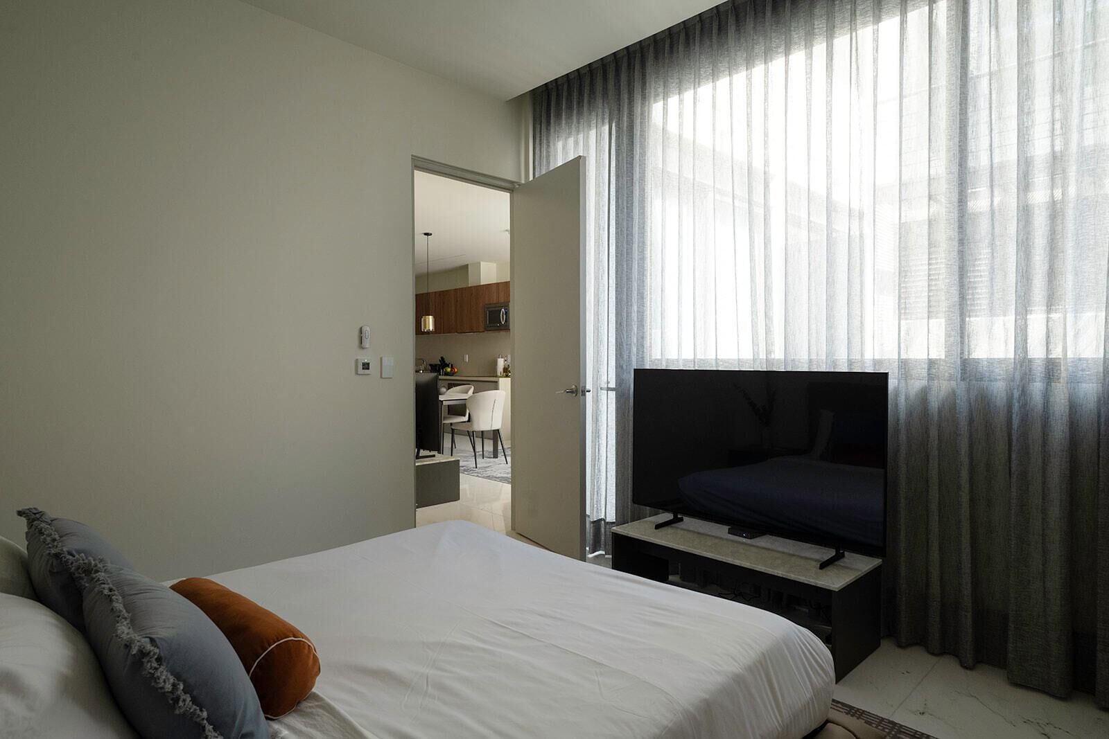 Une chambre d’hôtel avec un lit, une télévision et une vue sur une cuisine et un coin repas, grâce à une porte ouverte.