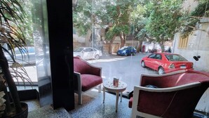 A room with a view of a street, two red chairs, a small round table, and a potted plant. - Tiab Masr Hotel (Giza)