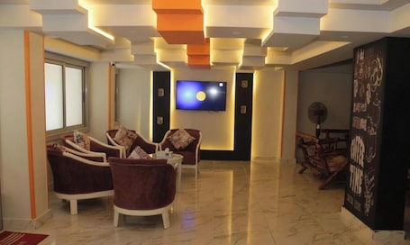 A modern living room with a flat-screen TV, comfortable seating, and a decorative wall.. Tiab Masr Hotel