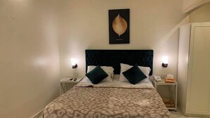 A bedroom with a bed, two bedside tables, a nightstand, a wall-mounted artwork, and a wardrobe. - Tiab Masr Hotel (Giza)