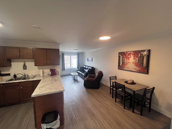 A modern kitchen with a marble countertop, wooden cabinets, and a dining area with a table and chairs.