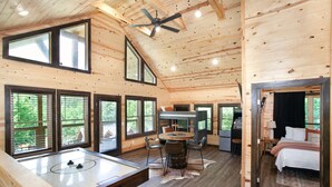 A wooden cabin with a dining area, kitchen, and a bedroom with a bed and nightstand. - Smoky Ridge Hideaway: Views, Hot Tub, Game Room! (Sevierville)