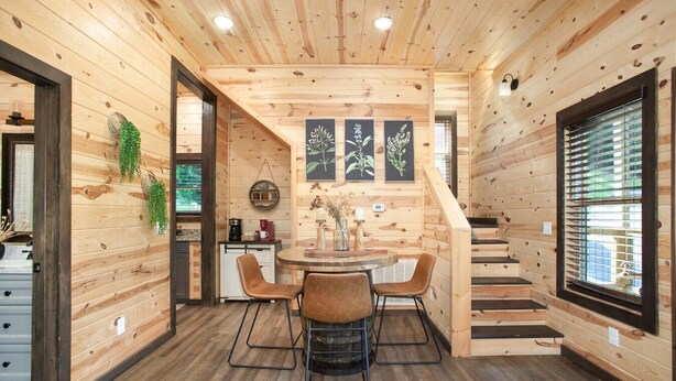A wooden interior with a round dining table, two chairs, a staircase, and framed botanical prints on the wall. - Smoky Ridge Hideaway: Views, Hot Tub, Game Room! (Sevierville)