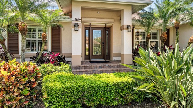 A two-story house with a beige facade, a brown door, and a number '1879' above the entrance. - Tranquility where relaxation meets coastal charm (Marco Island)