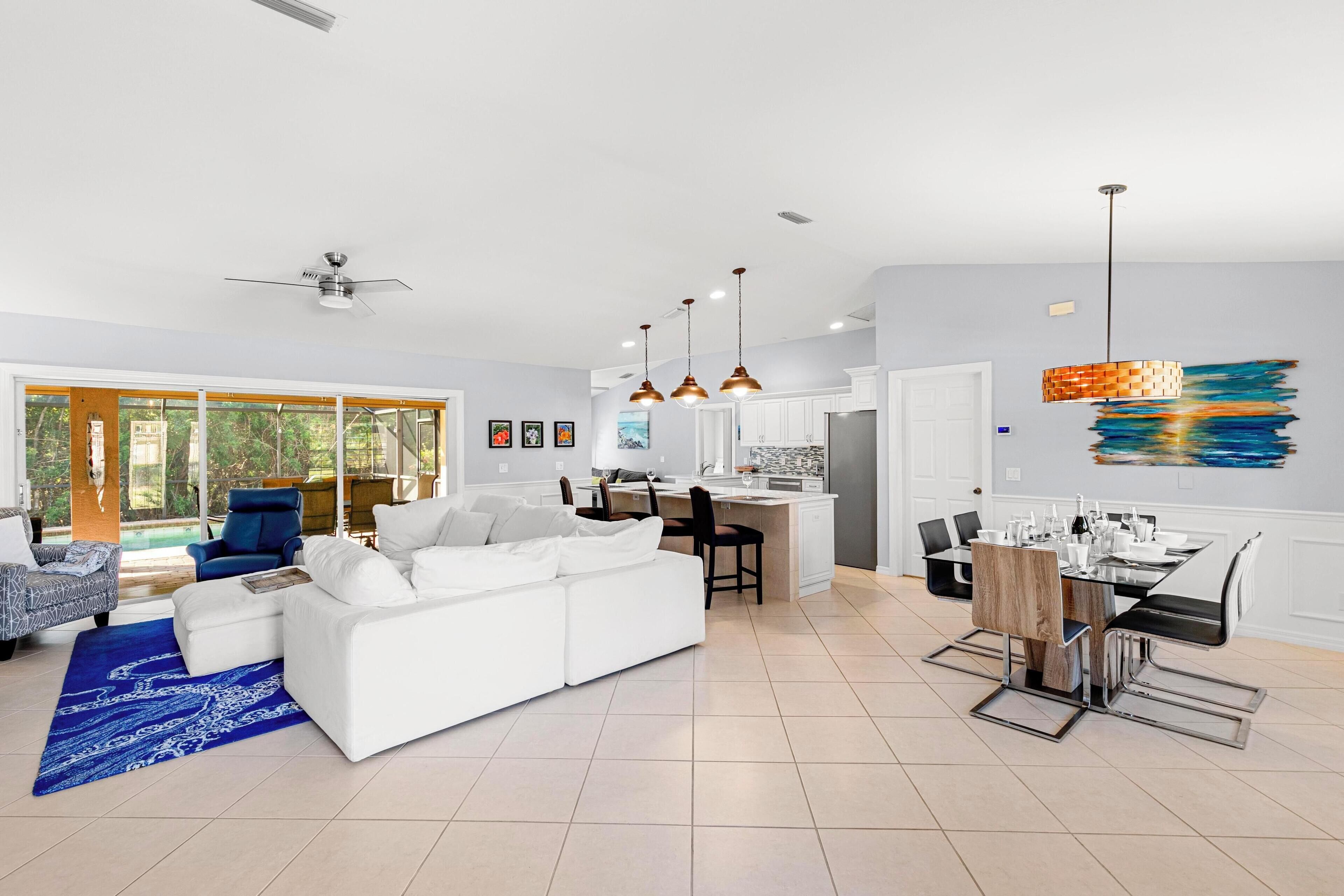 Un salon moderne avec un canapé blanc, un tapis bleu et un coin repas comprenant une table et des chaises.