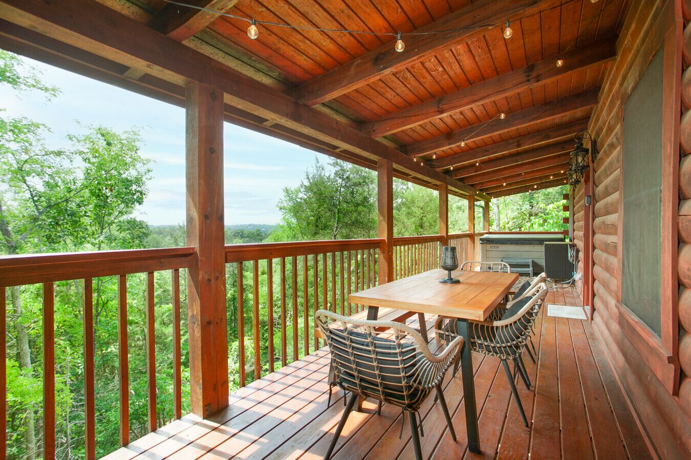 Um deck de madeira com mesa e cadeiras, com vista para uma área arborizada.