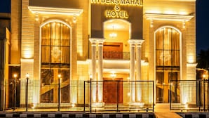 El exterior del Hyder's Mahal & Hotel de noche, mostrando una entrada imponente con un gran arco, columnas y una fachada bien iluminada.