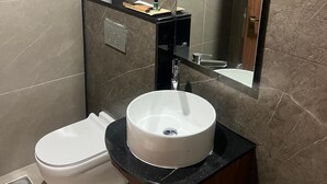 Un baño moderno con inodoro blanco, un lavabo redondo y un espejo encima.