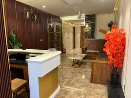 Zona de recepción con escritorio, asientos y una planta en maceta.