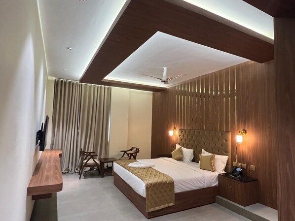 A modern hotel room with a large bed, a desk, and a chair. - Hyders Mahal and Hotel (Thanjavur)